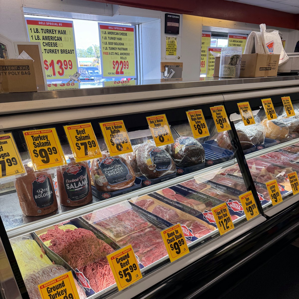 Behind the deli counter with specials board and cash jar